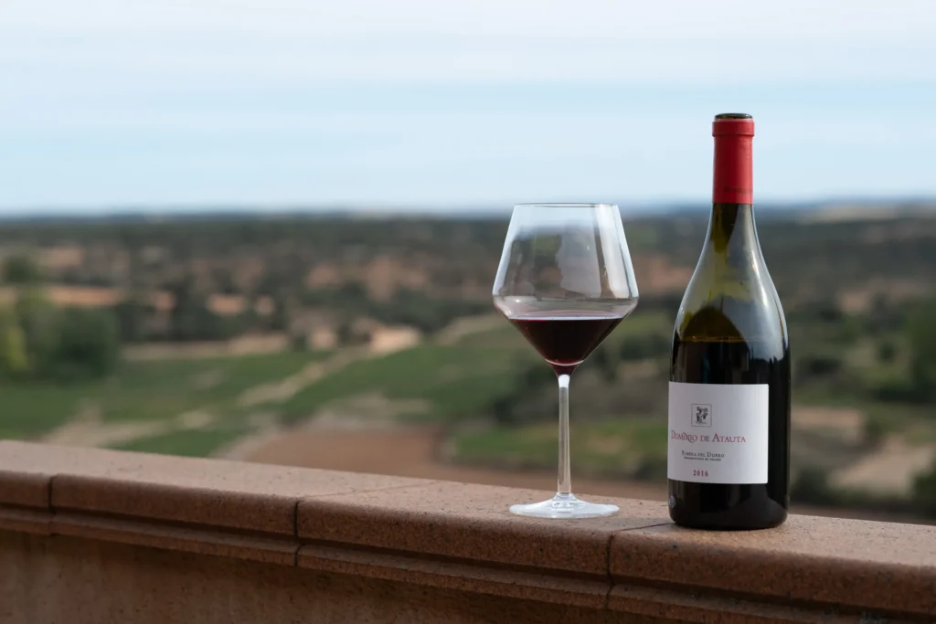 Botella de un vino Ribera del Duero de Dominio de Atuata junto a una copa.
